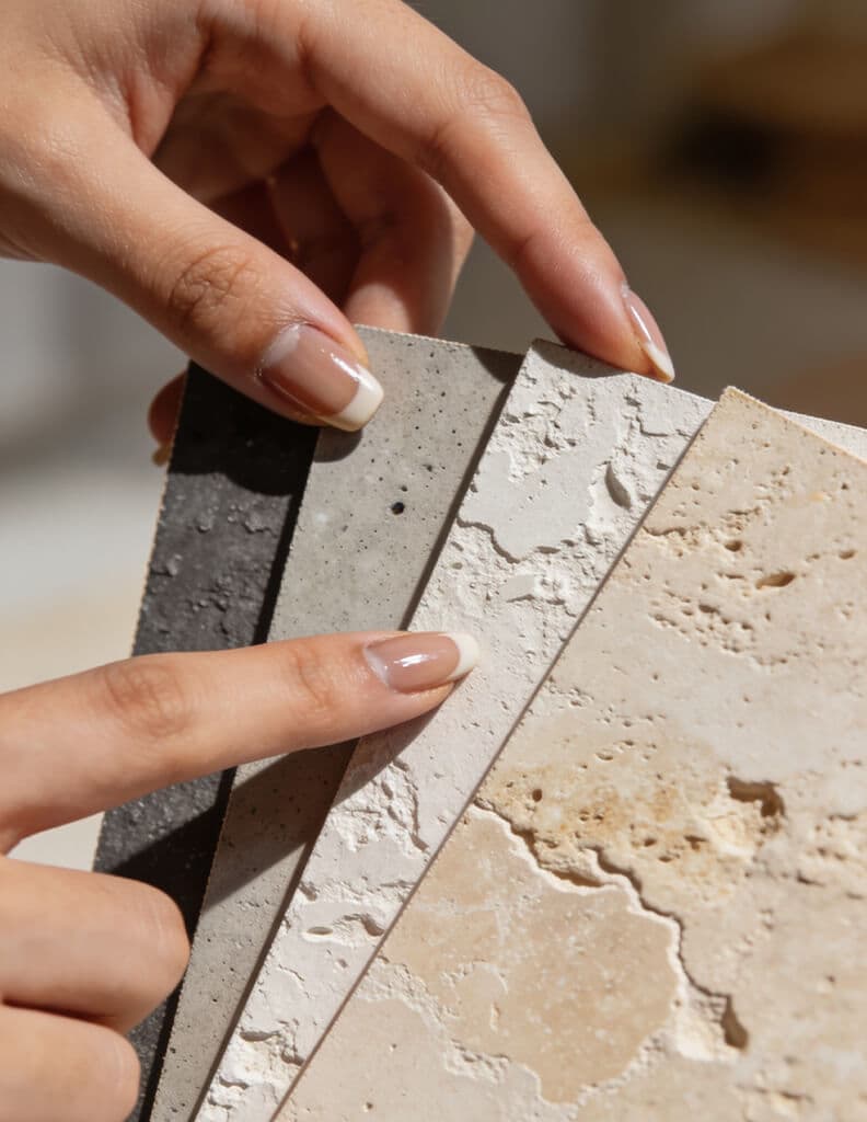 Concrete and travertine textured sample boards held in natural light
